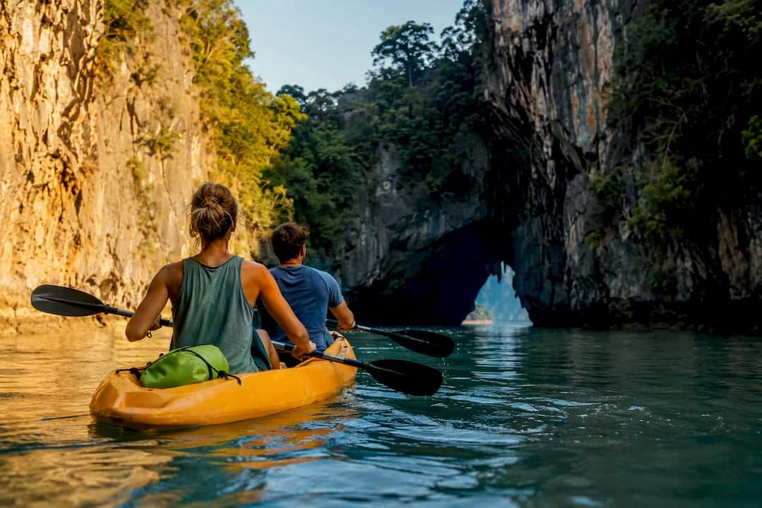 Kayakers approaching a limestone hong in Phang Nga Bay