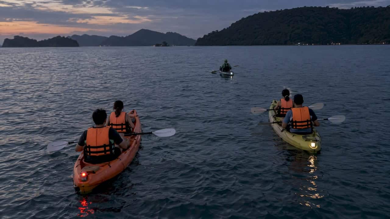 Kayaks maintaining safe spacing after dark