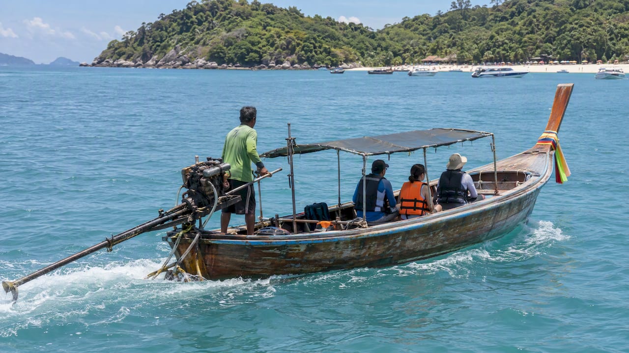 Traditional longtail carrying guests toward Coral Island
