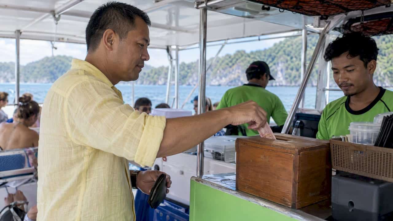 Guest places cash in a boat crew tip box